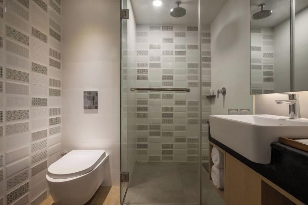 Un bagno moderno con doccia vetrata, un water bianco e un lavabo con piano in nero.