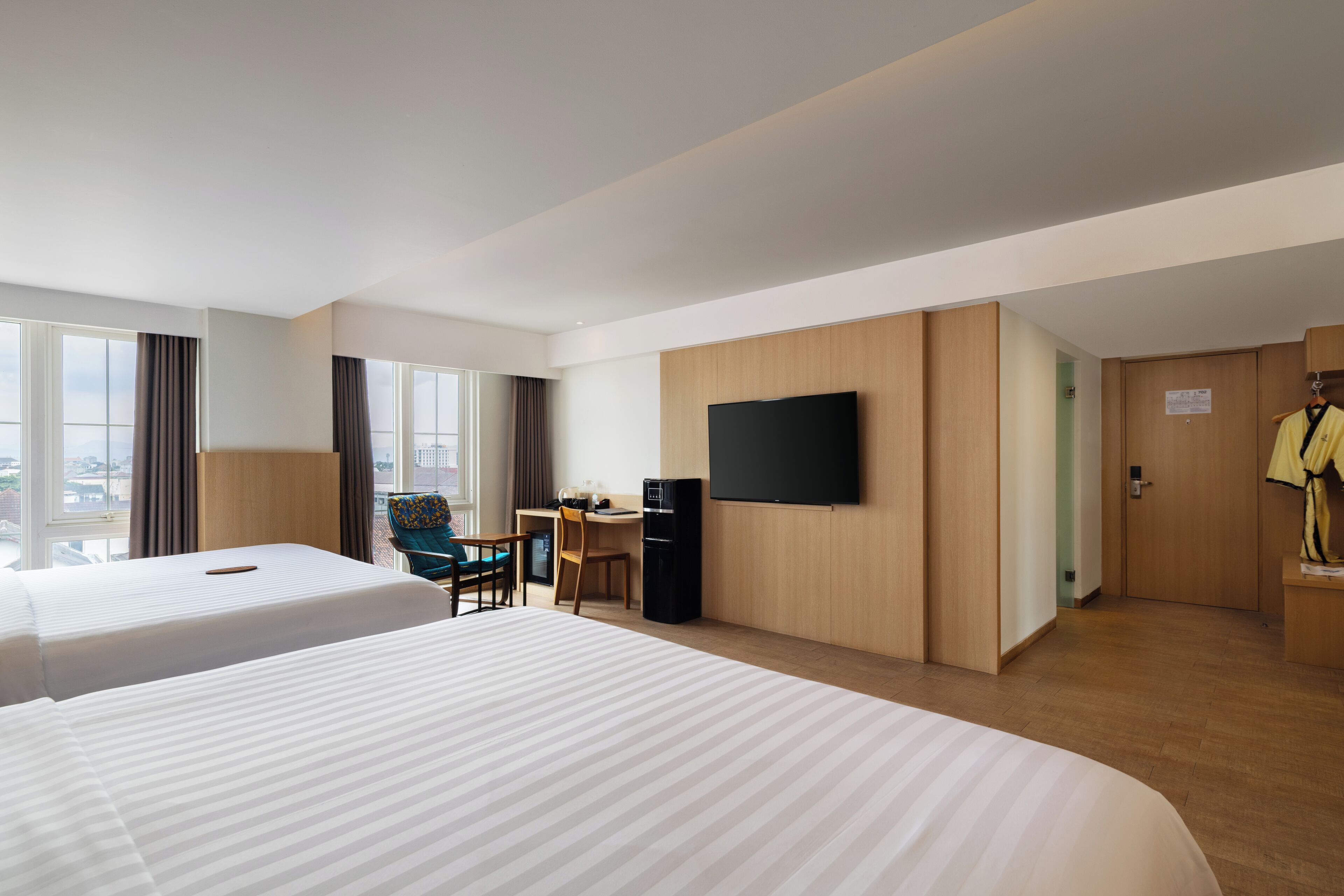 Habitación de hotel con dos camas, un escritorio, una silla, un televisor y un armario.