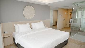 A modern hotel room with a large bed, a round wall decoration, and a glass partition.