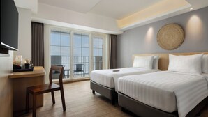 A hotel room with two beds, a desk, a chair, and a large window with a view. - Aveta Hotel Malioboro (Yogyakarta)