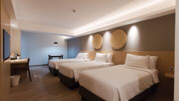 A hotel room with three beds, a desk, and a chair.