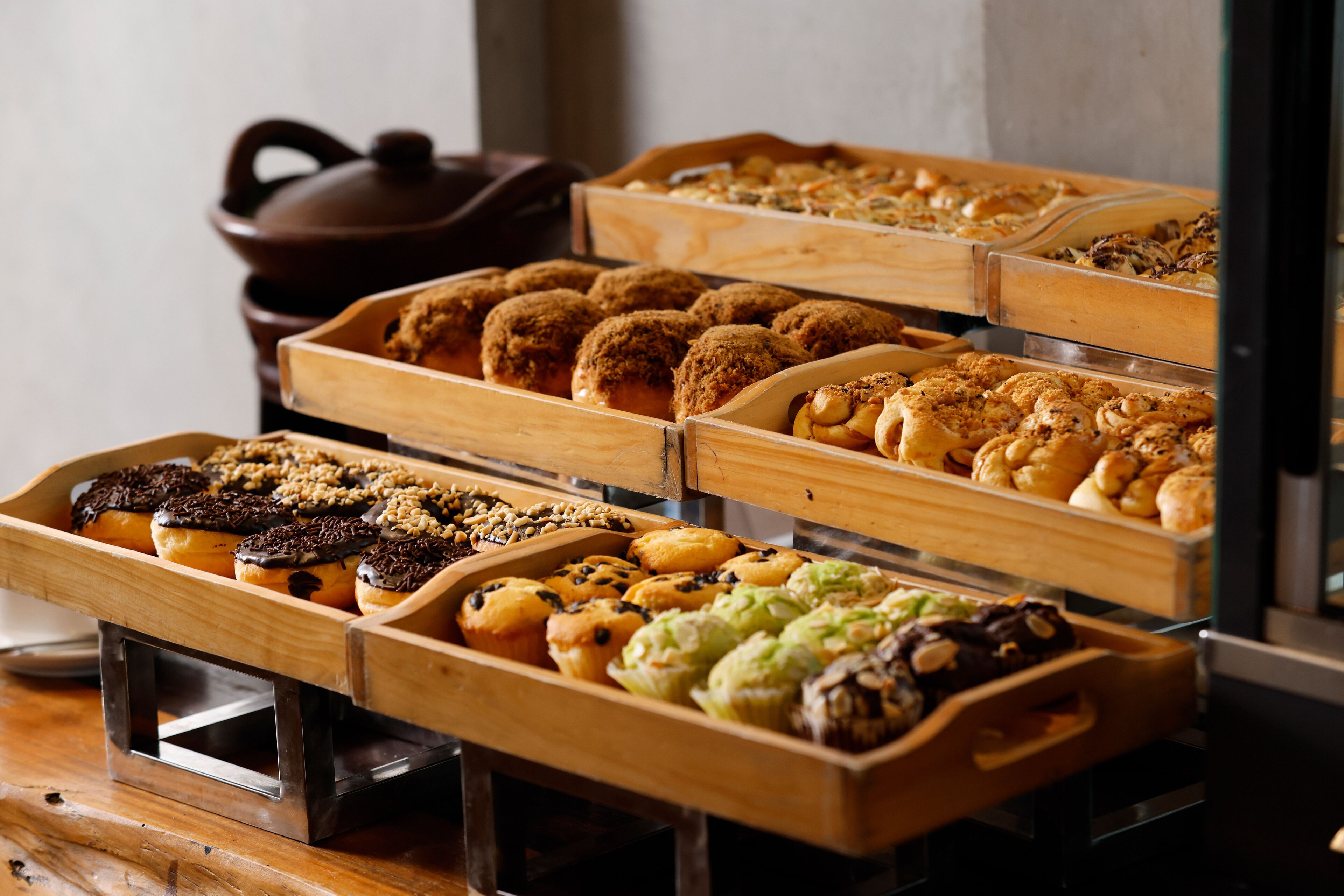 A bakery display with various baked goods in wooden trays.
