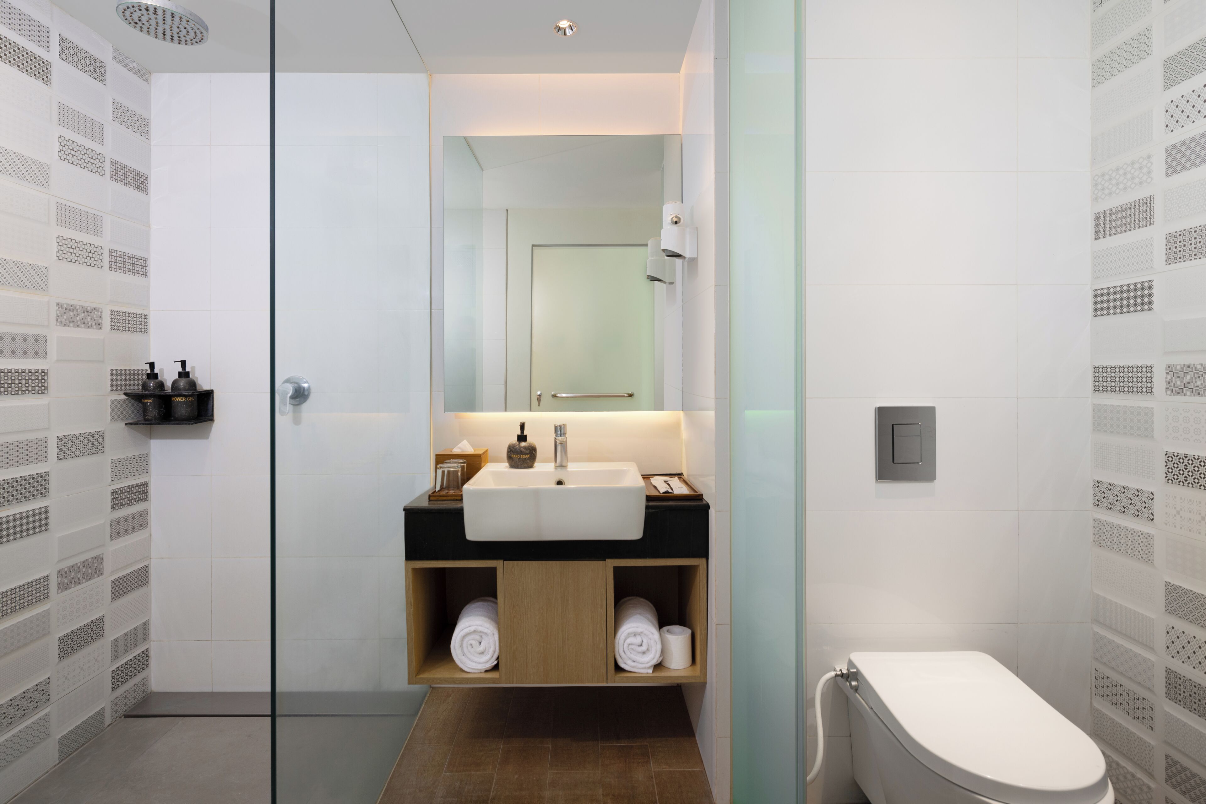 Un bagno moderno con cabina doccia in vetro, un lavandino bianco su piano nero e un water.