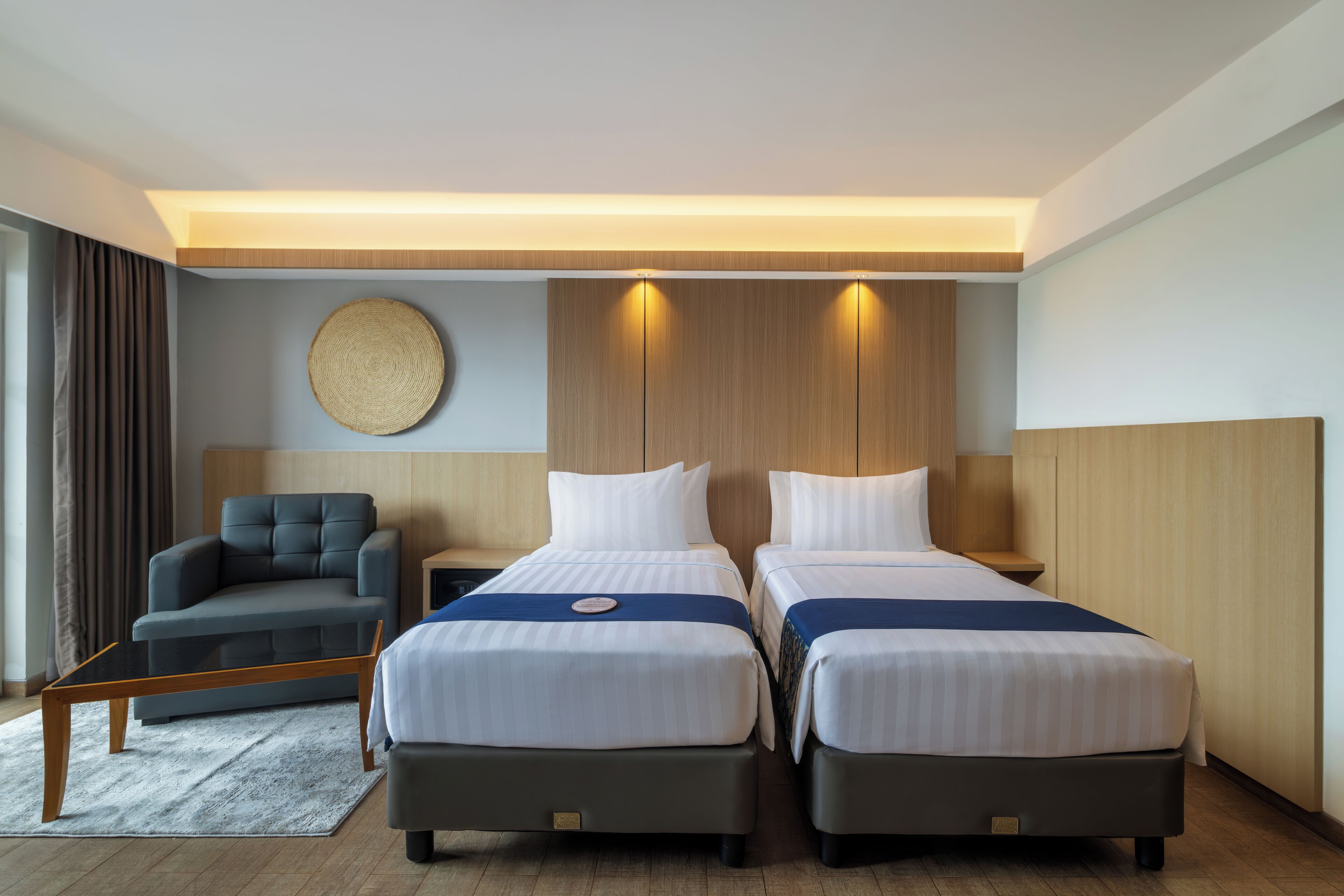 Une chambre d’hôtel avec deux lits, un canapé, un élément de décoration circulaire fixé au mur et un plafond en bois.