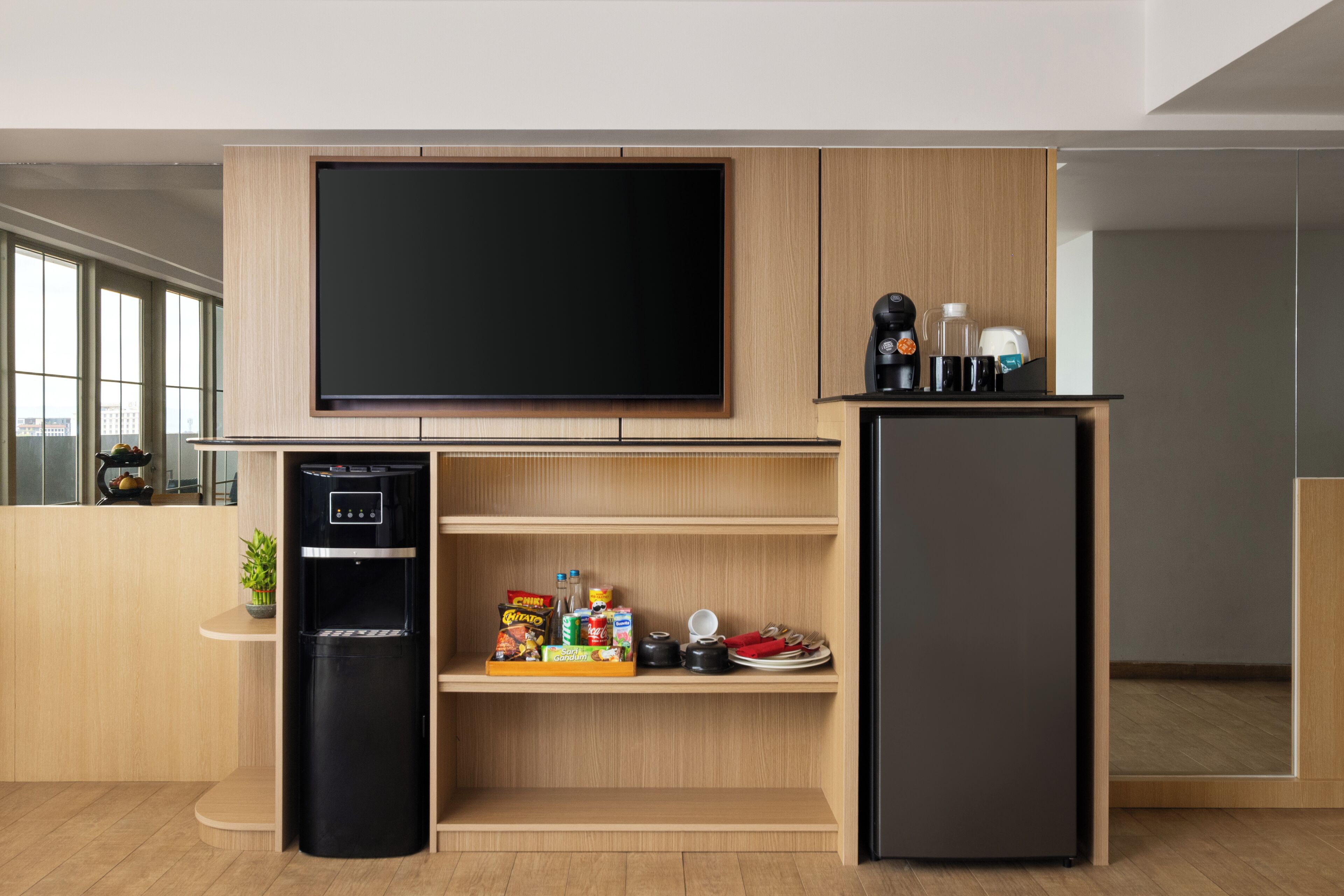 Cozinha moderna com televisão embutida, geladeira e máquina de café.