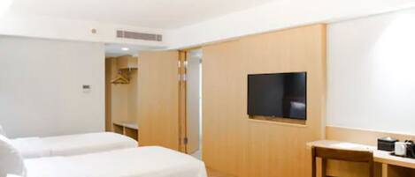 Habitación de hotel con dos camas, un televisor, un escritorio de madera y un armario.