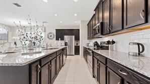 Una cocina moderna con armarios de madera oscura, una isla grande y un salpicadero de azulejos blancos.