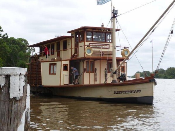 A large, multi-deck houseboat with a cabin and upper deck, docked at a pier. - Omaroo Apartment (Mannum)