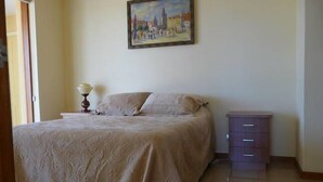 Une chambre à coucher avec un lit, une table de chevet, une commode et un tableau au mur.