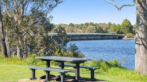 A picnic table by a lake with a bridge in the background. - 2-18 Mangrove Street (EVANS HEAD)