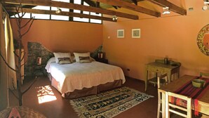 Ein Schlafzimmer mit einem Bett, einem kleinen Tisch, einem Stuhl, einem Teppich und einer Steinwand.