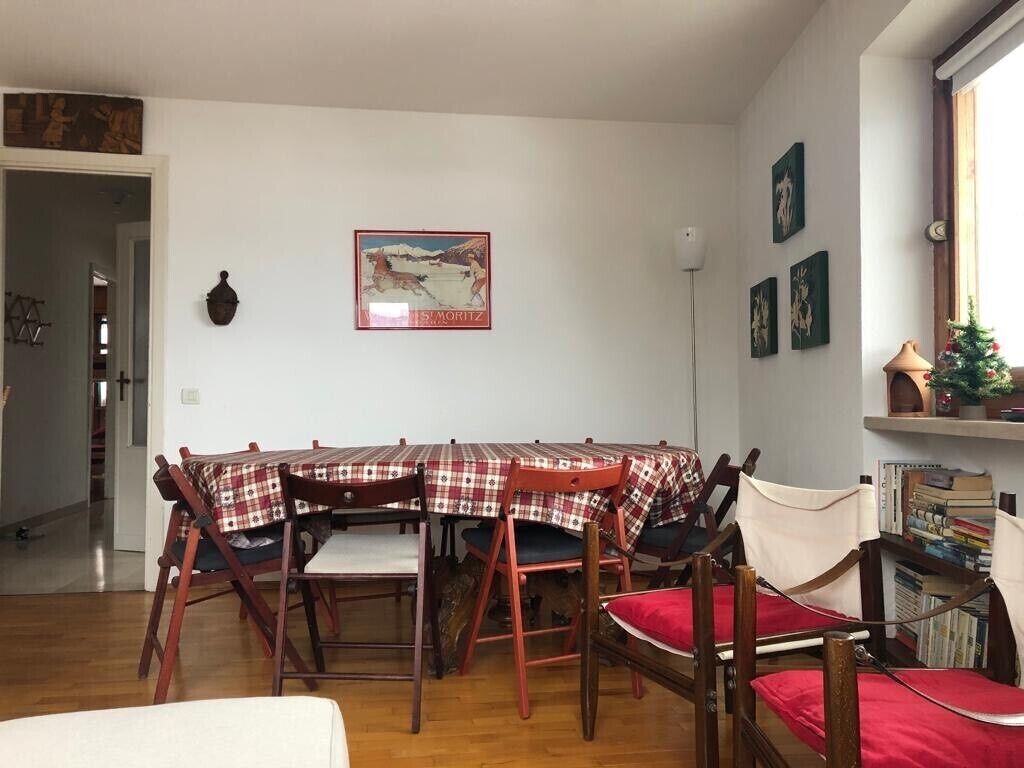 Ein Essbereich mit einem runden Tisch, bedeckt mit einer karierten Tischdecke, umgeben von Holzkästen mit roten Kissen.