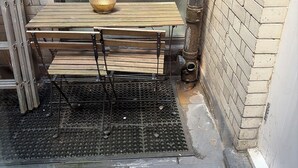 Paredes de tijolo com grade de metal e mesa de vidro com bancos.