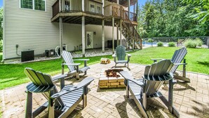 A patio with Adirondack chairs, a fire pit, and a wooden deck. - Private heated pool, Lake Michigan, tram to beach, fire pit, gas grill (South Haven)