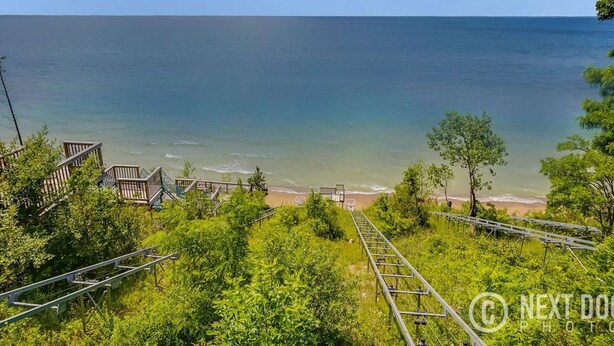 A coastal view with a beach, a staircase leading down to the beach, and a clear sky. - Private heated pool, Lake Michigan, tram to beach, fire pit, gas grill (South Haven)