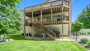 A two-story house with a wooden deck and a staircase. - Private heated pool, Lake Michigan, tram to beach, fire pit, gas grill (South Haven)