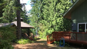 A cabin with a wooden deck, surrounded by dense forest.