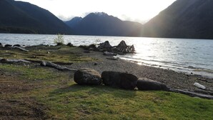 A lakeside view with mountains in the background and a rocky shoreline.