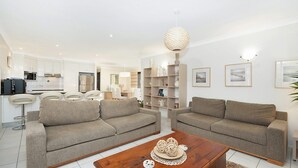 A modern living room with two sofas, a coffee table, and a kitchen in the background.