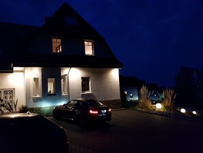 A modern house with a car parked in the driveway at night. - Ferienwohnung Villa Am Golfplatz (Bad Harzburg)