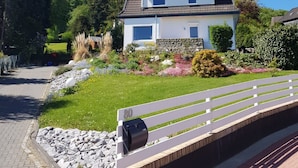 A two-story house with a tiled roof, surrounded by a well-maintained garden with various plants and flowers. - Ferienwohnung Villa Am Golfplatz (Bad Harzburg)