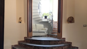 Eine Treppe führt zu einem Balkon mit einer gemusterten Couch und einem Blumentopf.