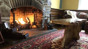Una habitación acogedora con chimenea de piedra, una máquina de escribir y una mesa de madera.