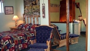 Een kamer met een bed, een stoel, een spiegel en een schilderij aan de muur.
