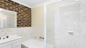 Ein Badezimmer mit weißem Waschtisch, einer Badewanne und einer Dusche mit Glastrennwand.