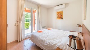 A bedroom with a bed, a nightstand, a lamp, a window with curtains, and a poster on the wall. - Villa du Bonheur for 8 people with private pool (Vallon-Pont-d'Arc)