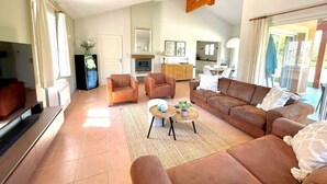 A living room with sofas, a coffee table, and a TV. There is a kitchen area in the background. - Villa du Bonheur for 8 people with private pool (Vallon-Pont-d'Arc)