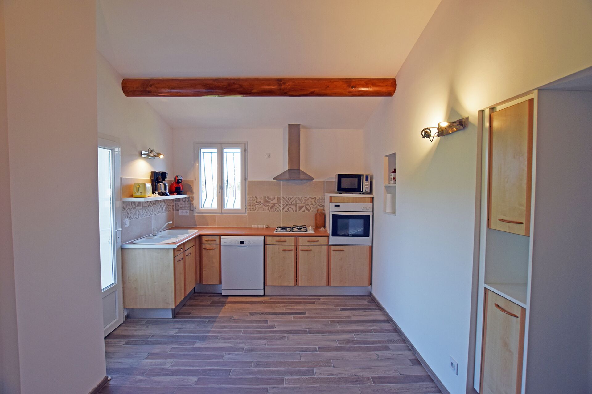 Une cuisine étroite avec des meubles de rangement en bois, un lave-vaisselle, un four à micro-ondes et une cuisinière à gaz.