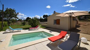 Zona de piscina con sillones de descanso y un pequeño edificio con antena parabólica.