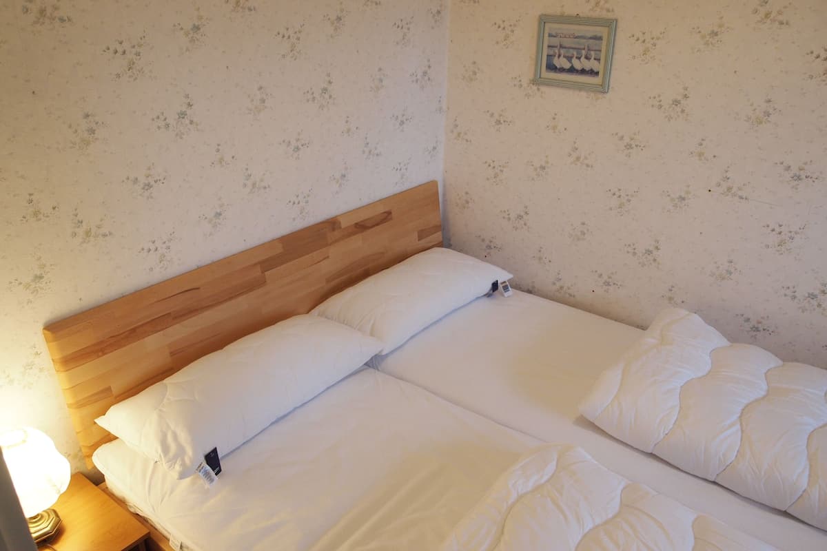 A double bed with white bedding, a wooden headboard, and a small bedside table with a lamp.
