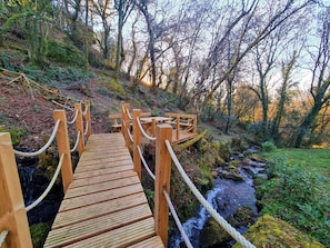 A wooden bridge with rope railings over a stream in a forested area. - To Pontiga | Rural house (Vilasantar)