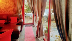 A cozy room with a red sofa, a red rug, and a stone wall.