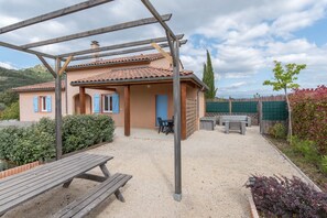 Un espace extérieur accueillant, avec une pergola, un banc en bois et une table.