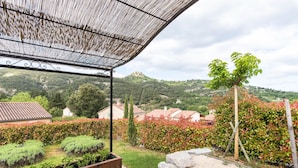 A covered outdoor area with a view of a garden, a wooden bench, and a stone pathway. - Villa Acacia for 8 people close to the communal swimming pool (Vallon-Pont-d'Arc)