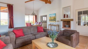 A spacious living room with a brown sofa set, a wooden coffee table with a vase of flowers, and a fireplace. - Villa Acacia for 8 people close to the communal swimming pool (Vallon-Pont-d'Arc)