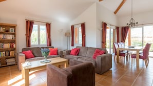 A spacious living area with a sofa set, a dining table with chairs, and a bookshelf. - Villa Acacia for 8 people close to the communal swimming pool (Vallon-Pont-d'Arc)