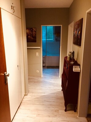 Un corridoio con pavimento in legno che conduce a una stanza con un armadietto blu e un quadro.
