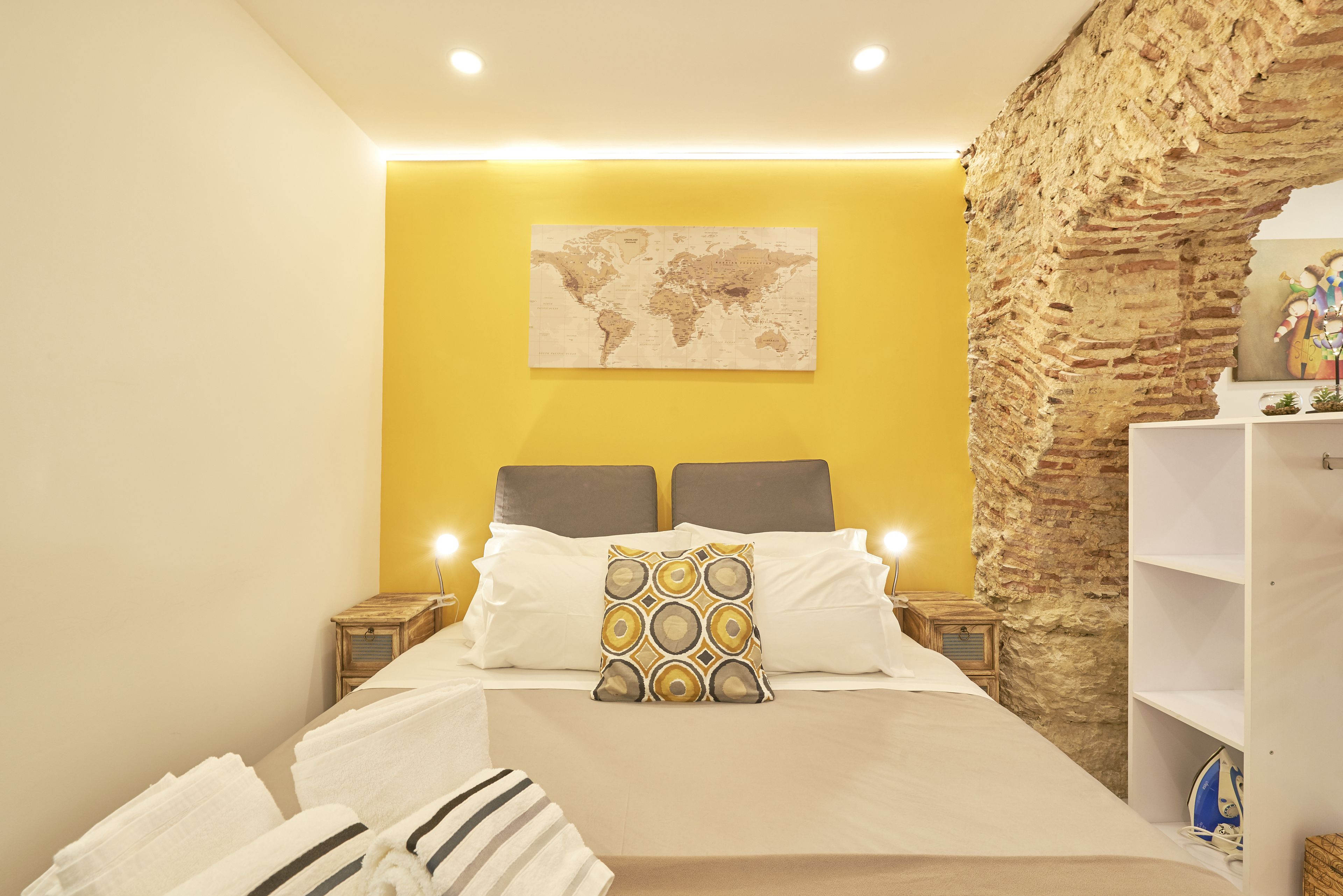 A modern bedroom with a large bed, a world map on the wall, and a brick wall feature.