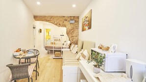 Un espacio habitable compacto con cama, zona de comedor, microondas y pequeña kitchenette.