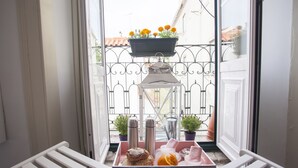 Un balcón con una bandeja de comida, una planta en maceta y un colgador con flores.
