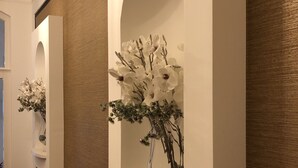 A modern interior with a white wall, a large window, and a decorative white flower arrangement. - Aquasol Resort (Mosonmagyarovar)