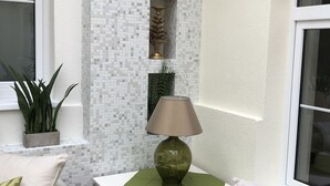 A corner room with a white tiled wall, a small table with a lamp, and two sofas with cushions. - Aquasol Resort (Mosonmagyarovar)