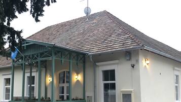 Ein Gebäude mit einem Ziegeldach, einer Veranda mit grünen Geländern und mehreren Fenstern mit Außenbeleuchtung.