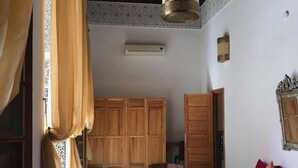 A room with a red sofa, a patterned rug, wooden furniture, and a hanging light fixture. - Riad Jasmins & Spa (Fes)