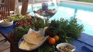 A poolside table with various food items and a decorative glass bowl. - Villa “Le Terrazze” (Lumio)