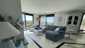 A modern living room with a sectional sofa, a small table, and a cabinet. - Villa “Le Terrazze” (Lumio)